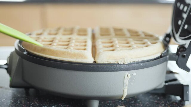Making homemade waffles in an electric waffle maker.