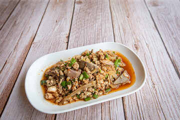 Thai food, spicy minced pork salad (Larb Moo) in white plate on wooden table, popular local food in northeastern Thailand