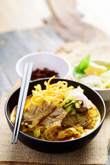 Northern Thai food (Khao Soi), Spicy curry noodles soup with coconut milk and beef eating with crispy egg noodles, pickled mustard, shallots and lime