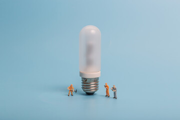 Glass bulb and miniature workers on blue background
