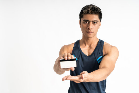 asian young man wearing sportswear stand facing forward look the camera present credit card with two hands on isolated background