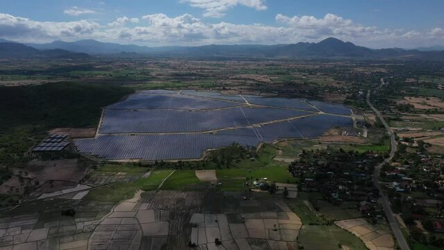 Solar panel produces green, environmentaly friendly energy from the setting sun. View from drone. Landscape picture of a solar plant that is located inside a valley, Krong Pa, Gia Lai, Vietnam