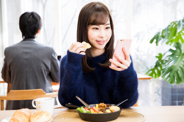 食事しながらスマホをする女性客