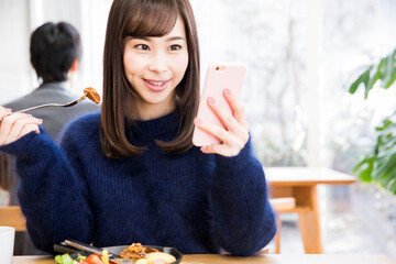 食事しながらスマホをする女性客