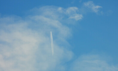 Fototapeta premium Airplane flying in the clear blue sky and contrail against, Engine exhaust contrails forming behind, Jet contrails or trails over blue sky and clouds.