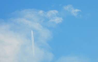 Airplane flying in the clear blue sky and contrail against, Engine exhaust contrails forming behind,  Jet contrails or trails over blue sky and clouds.