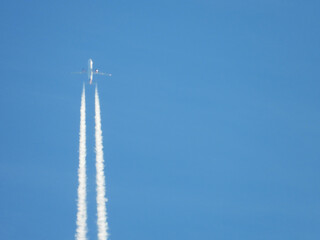 Airplane flying in the clear blue sky and contrail against, Engine exhaust contrails forming...