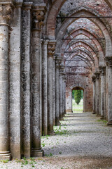 Close up of the secondary nave of an ancient gothic church, with a long row of columns and concentric pointed arches
