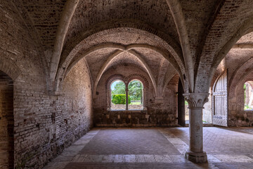 Interior of an ancient italian monastery, with a cross vaulted hall and a mullioned window