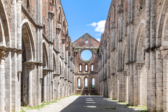 Symmetrical view of the main nave of an ancient cathedral in ruins and with no roof, under a blue summer sky