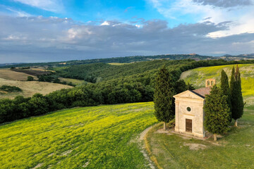 Aerial view of the tuscanian countryside with the chapel of Vitaleta surrounded by cypresses in Val D'Orcia at sunset