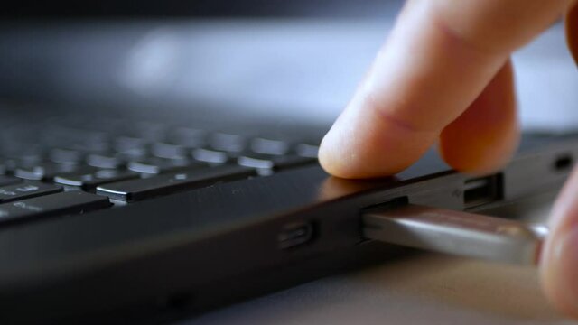 Caucasian man inserting an usb pen drive in to a gaming laptop computer.