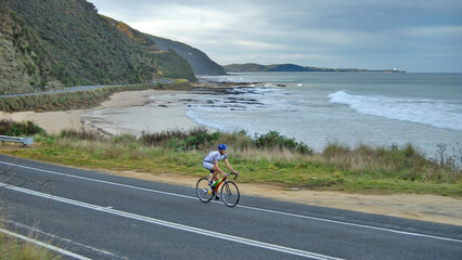 lone cyclist on the scenic winding Great Ocean Road in Victoria Australia