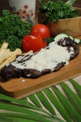 Grilled steak with mozzarella spills served on wooden tray