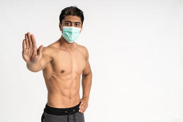 asian muscular man wearing a mask with a refuse hand gesture and one hand on the waist stand facing forward and look the camera on isolated background