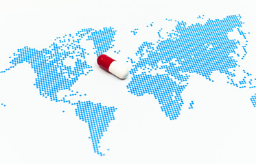 Red capsule medicine on the blue dots patterned world map. The concept of novel drug against global pandemic and infectious diseases © HYUNGKEUN
