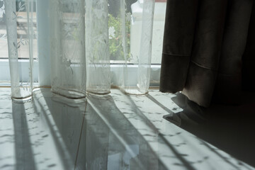 White lace curtain in the afternoon form a soft shadow on the floor