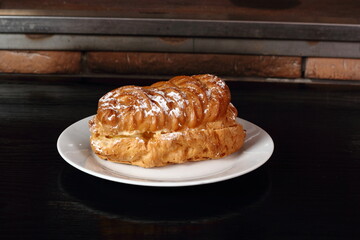 Eclair filled with pastry cream (custard) and topped with icing sugar