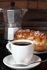 Coffee cup with espresso and eclair