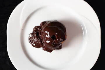 Profiterole with chocolate ganache frosting.  Choux pastry ball with custard filling and chocolate sauce icing. Directly Above.