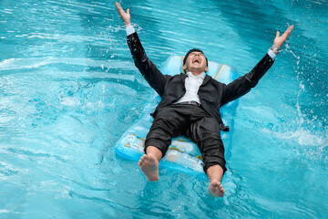 a man in a suit is resting in the pool on an inflatable blue mattress