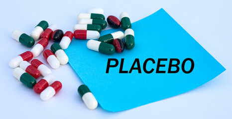 PLACEBO words on a blue sheet of paper against the background of multicolored tablets