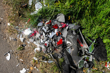 Car or motorcycle crash. A pile of debris on the roadside. Reflection of sunlight on the glass.