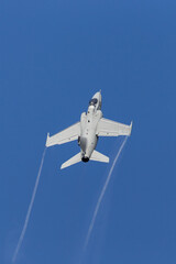 Fighter jet climbing vertically into the blue sky.