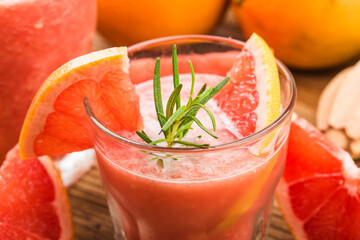 Grapefruit juice with rosemary and ice in a glass on the table. Refreshing summer cocktail