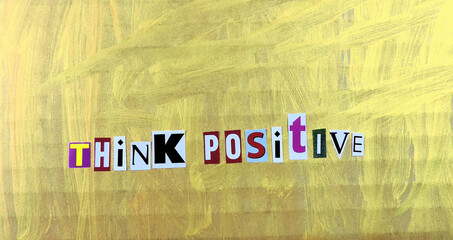Think positive word paper letters on a painted gold surface