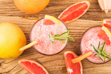Grapefruit juice with rosemary and ice in a glass on the table. Refreshing summer cocktail