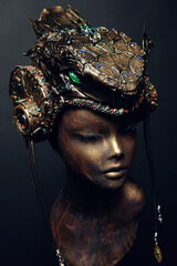 Bronze head of mannequin in decorated bronze headpiece, dark studio background