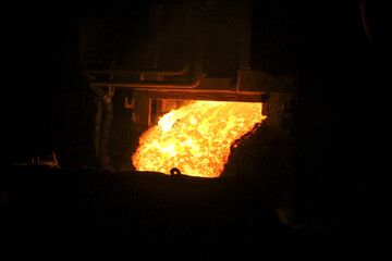 Hot steel pouring in steel plant. Molten metal poured from ladle. Metallurgical production, heavy industry, engineering, steelmaking.