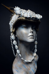 Head of mannequin in creative white headwear with feathers and pearls
