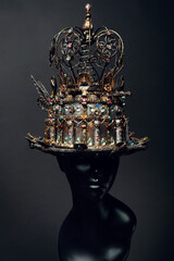 Mannequin in top-hat with wings and crown on black background