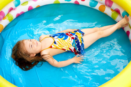 horizontal photo a girl lies in a children's multi-colored pool in full growth