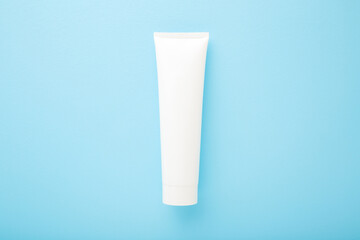 White plastic tube on light blue table background. Pastel color. Care about face, hands, legs and...