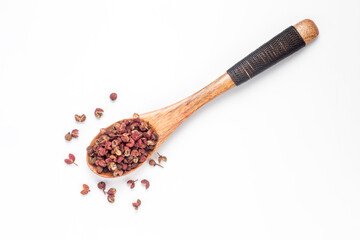 sichuan pepper (zanthoxylum bungeanum) in a wooden spoon isolated on white background. Chinese...