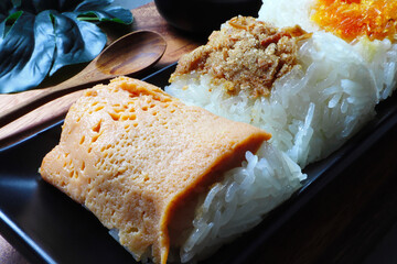 Sticky rice with egg custard , Shrimp sticky rice , Sticky rice with dried fish in the black square plate on the wooden tray with coconut milk with banana leaf
