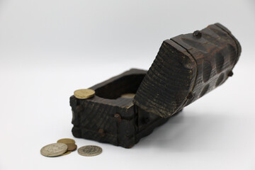 A treasure chest filled with coins, including dollars, on a white background.