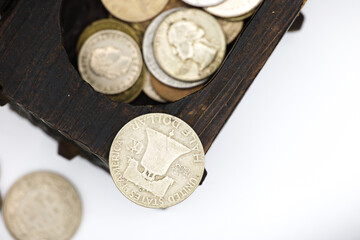 A treasure chest filled with coins, including dollars, on a white background.