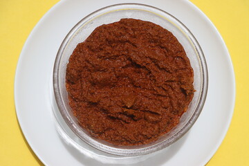 Red curry paste in glass bowl, basic ingredient for Indian curry or gravy made with various spices, tomatoes and onions.