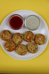 Appum or Appe, Appam or Mixed dal or Rava Appe served with green and red chutney. A Ball shape popular south Indian breakfast dish, Selective focus