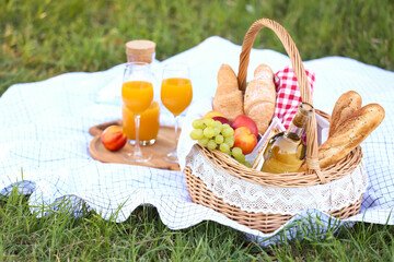 Basket with tasty food and drink for romantic picnic in park