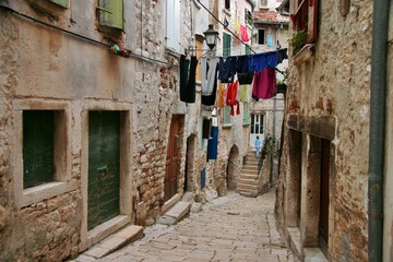 Fototapeta na wymiar A narrow European street with paving stones in the old town in Porec, Croatia