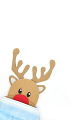 Cardboard cutout of Rudolph the red-nosed reindeer peeking while wearing a face mask. Covid during...