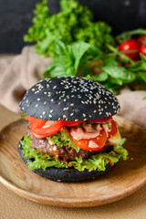 Tasty burger with black bun on plate