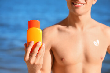 Handsome young man with sunscreen cream on sea beach