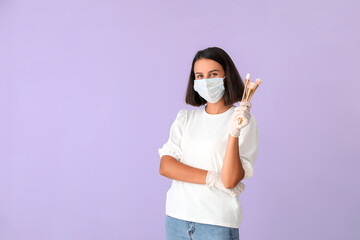 Female makeup artist wearing medical mask on color background. Coronavirus epidemic
