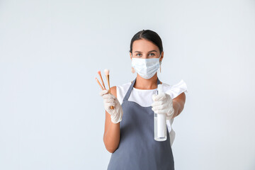 Female makeup artist wearing medical mask on light background. Coronavirus epidemic